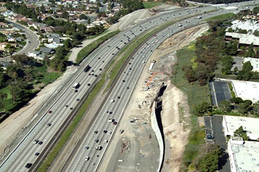 Overhead view of multi-lane highway with construction in progress at the right-side shoulder. 