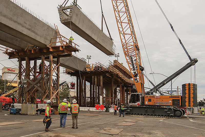 Crews hoist concrete girders into place along Genesee Avenue, to form the Trolley bridge. (February 2019)