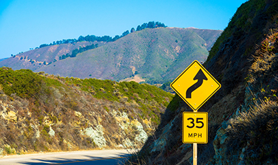 Yellow 35 mph sign with curved arrow on a country road in California.