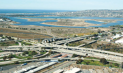 Sunny day aerial view of the I-5 and I-8 connector facing northbound with Mission Bay in the background.