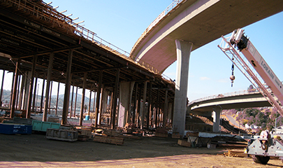 Photo of SR 52 construction showing intersection overpass of three bridges. One bridge appears completed, while one is almost complete, and another one is still in construction covered in wood framework.