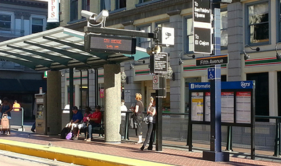 Trolley riders sitting and standing, waiting at the renovated station on a sunny afternoon.